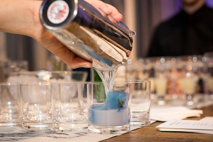 bartender preparing signature cocktail with blue icecube 